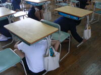 机の下に避難する高学年児童